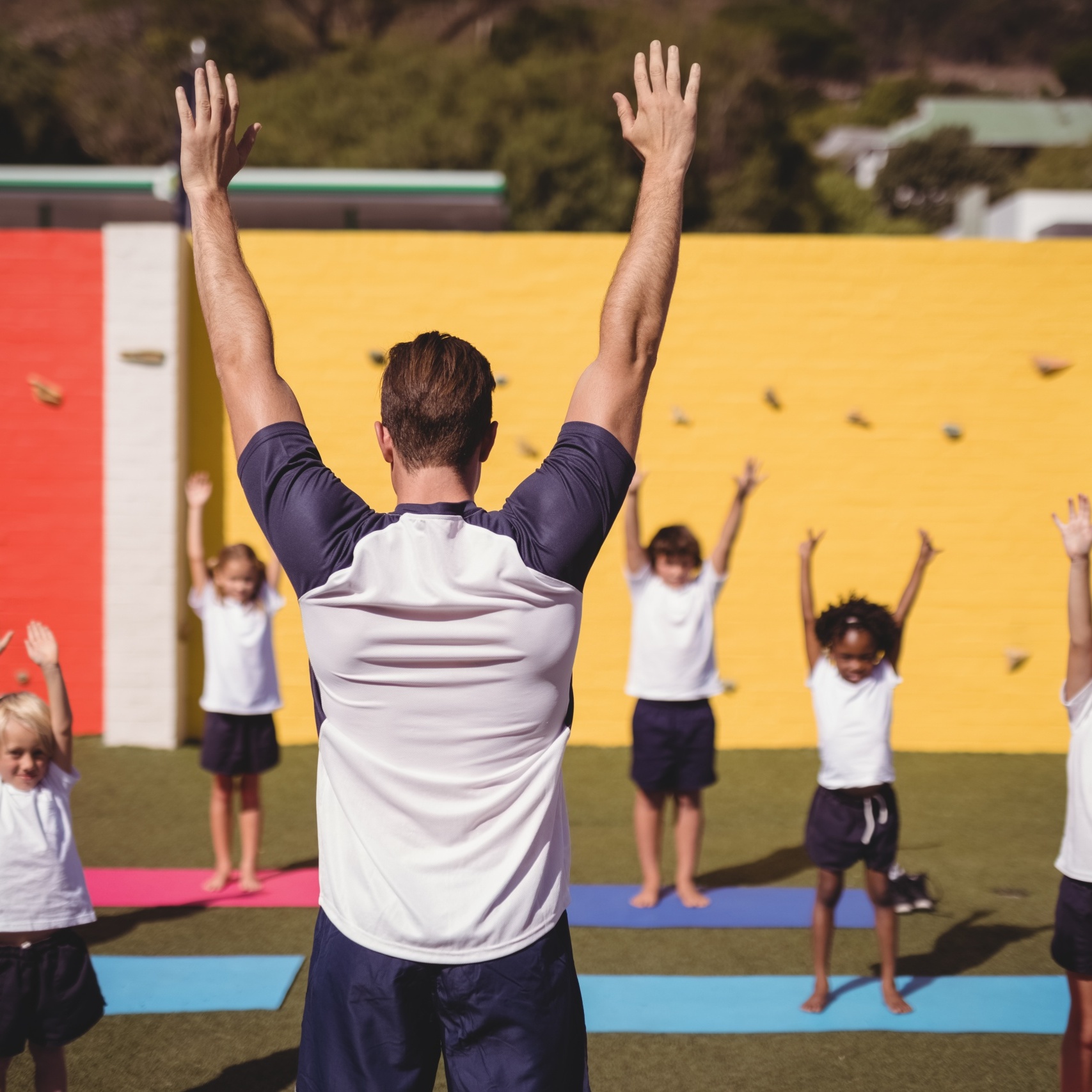 Coach teaching exercise to school kids in schoolyard